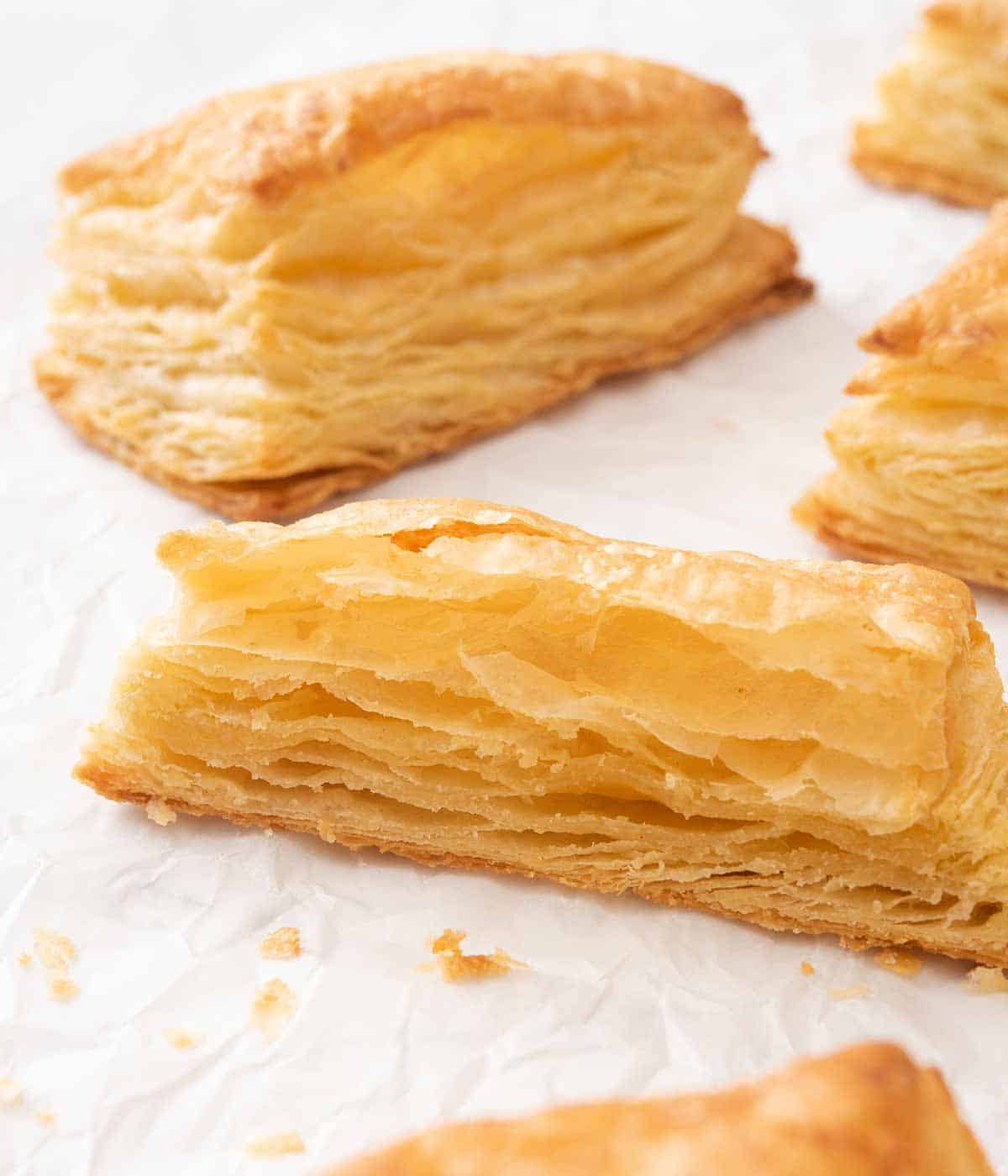 Puff pastry on a white surface with one cut in half, showing the flaky layers.