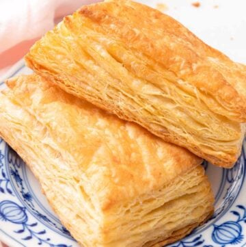 A blue and white plate with two puff pastries.