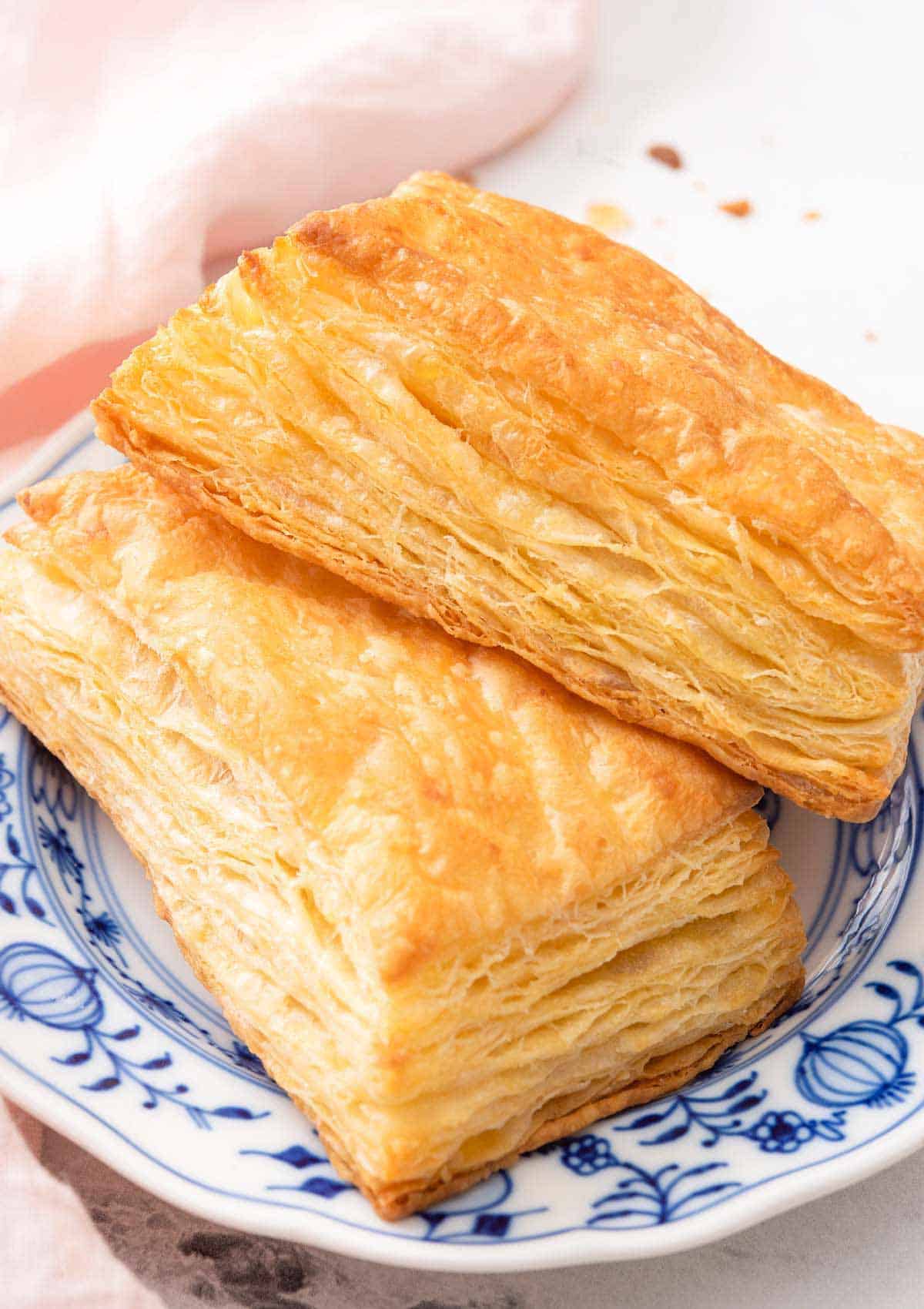 A blue and white plate with two puff pastries.