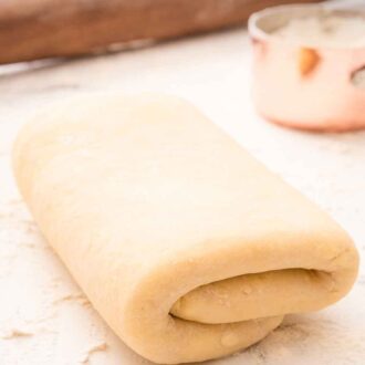 Pinterest graphic of a folded puff pastry on a floured surface.