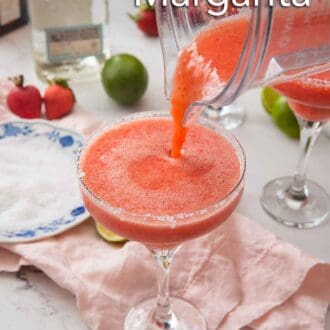 Pinterest graphic of a blender of strawberry margarita being poured into a glass with a plate of salt in the background and other ingredients.