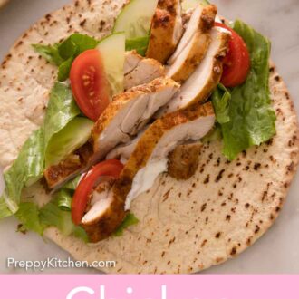 Pinterest graphic of a pita with chicken shawarma with lettuce, tomatoes, and cucumbers.