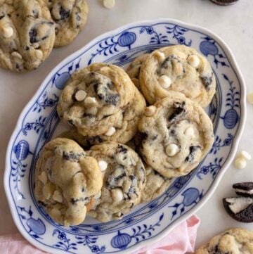 Overhead view of an oval platter of cookies and cream cookies with a couple scattered around it with oreos.