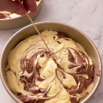 Pinterest graphic of a skewer mixing the batter in a cake pan to make a marble effect.