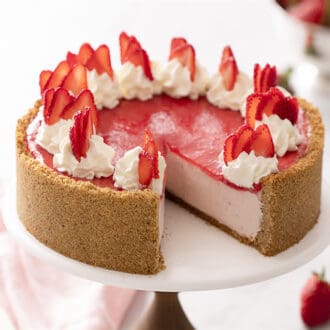 A no bake strawberry cheesecake with whipped cream dollops and strawberry slices on top.