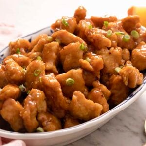 A platter of orange chicken with green onions.