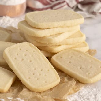 A group of delicious homemade shortbread cookies stacked on a marble surface with parchment paper.