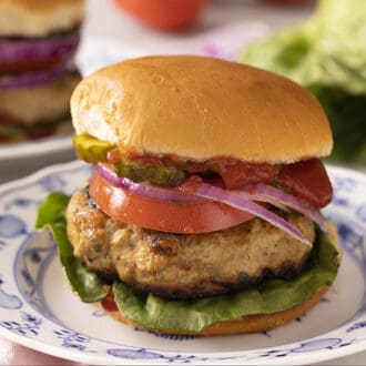 A delicious turkey burger on a blue and white plate.