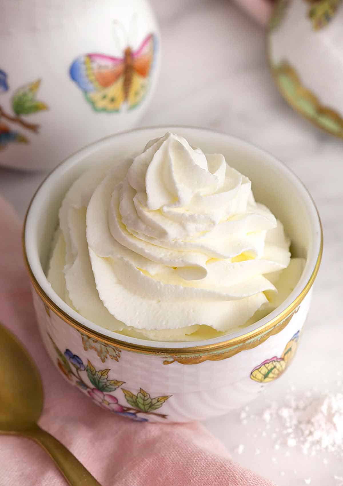 A bowl with flowers and butterflies containing whipped cream.