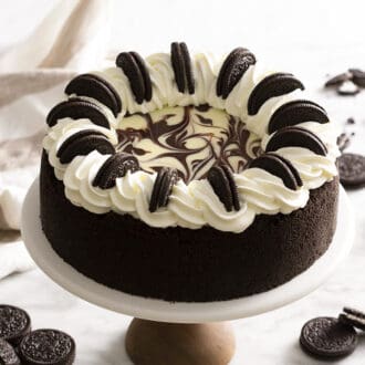 An oreo cheesecake sitting on a cake stand