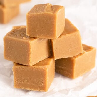 A stack of cubed peanut butter fudge on a crinkled piece of white parchment paper.