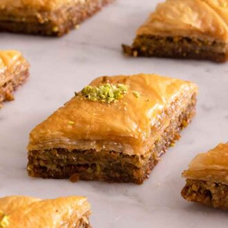 Multiple individual baklava pieces on a marble surface.