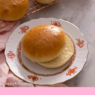 Pinterest graphic of a plate with a brioche bun, sliced in half, in front of a cooling rack with more buns.
