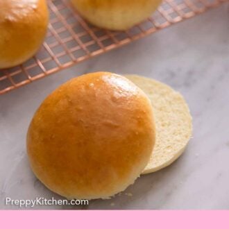 Pinterest graphic of a brioche bun cut in half in front of a cooling rack with more buns in the back.