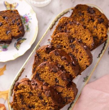 A serving platter with sliced chocolate chip pumpkin bread.