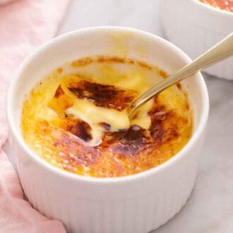 A crème brûlée with the top cracked with a spoon inserted.
