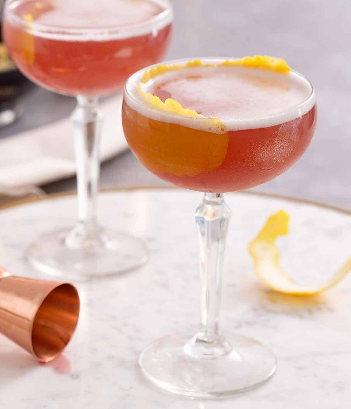 Two French martini in a cocktail glass with lemon peel as a garnish.
