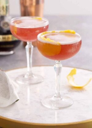 Two glasses of French martini with lemon garnish on a marble surface.