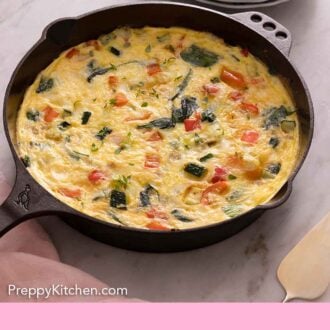 Pinterest graphic of a cast iron skillet with a frittata beside a stack of plates.