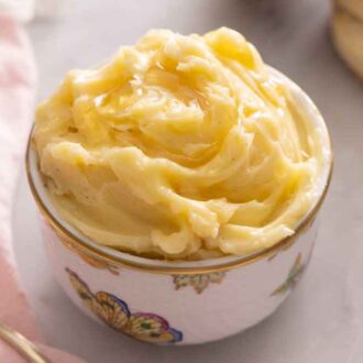 A bowl of honey butter beside a linen napkin and butter knife.