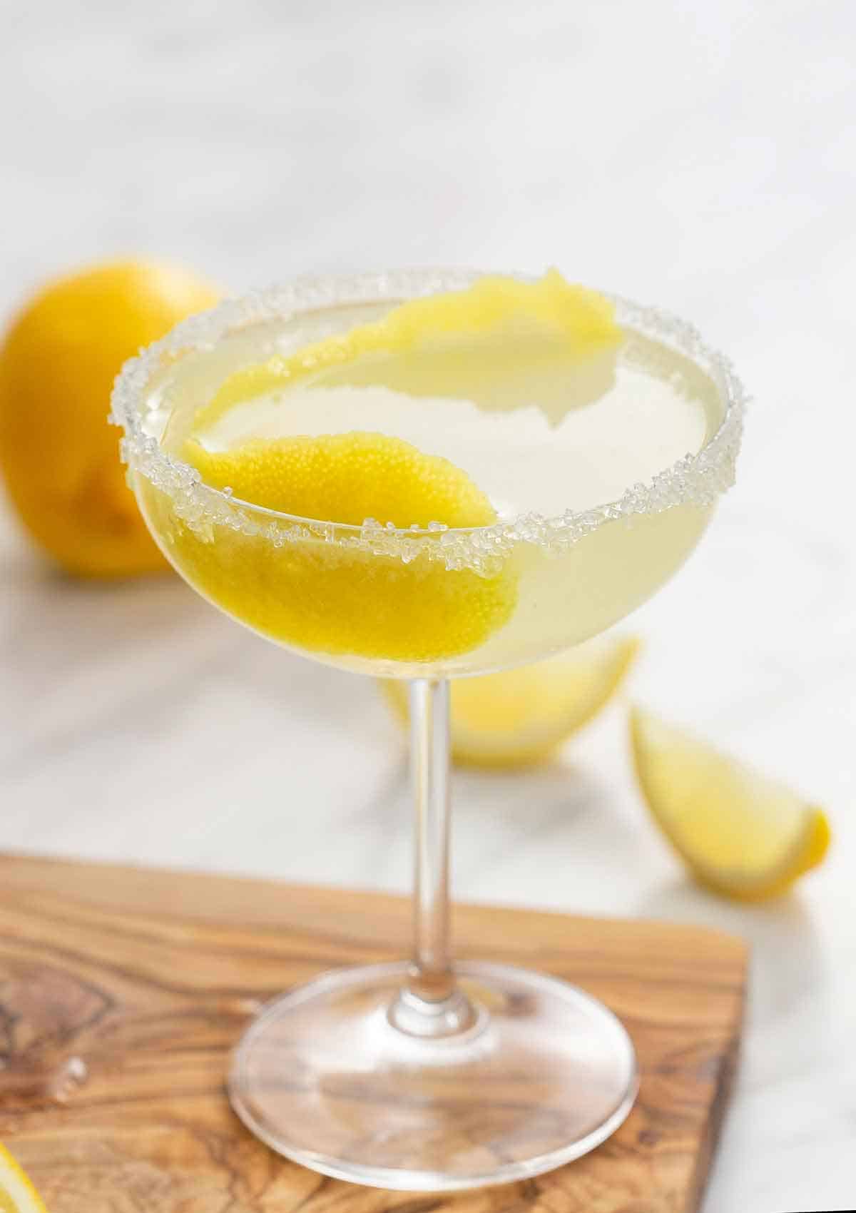 A glass of lemon drop martini with a lemon peel in the glass and a sugared rim.