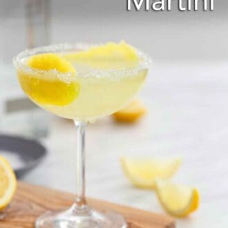 Pinterest graphic of the side view of a glass of lemon drop martini with lemon peel garnish on a wooden serving board.
