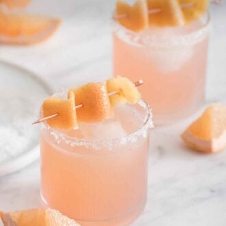 Pinterest graphic of two paloma cocktails on a marble surface with grapefruit wedges scattered around.