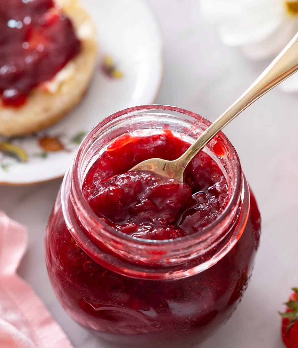 Overhead view of a mason jar of strawberry jam with a spoon inside.