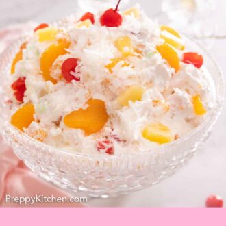 Pinterest graphic of a serving bowl of ambrosia salad with fruits and shredded coconut flakes.