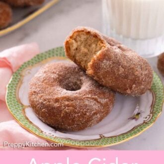 Pinterest graphic of two apple cider donuts, one with a bite taken out of it, on a plate in front of a glass of milk.