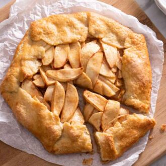 Overhead view of an apple galette with a slice cut but not removed from the serving board.