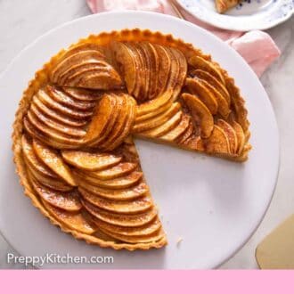 Pinterest graphic of the overhead view of an apple tart with a slice cut out of it and served on a plate behind it.