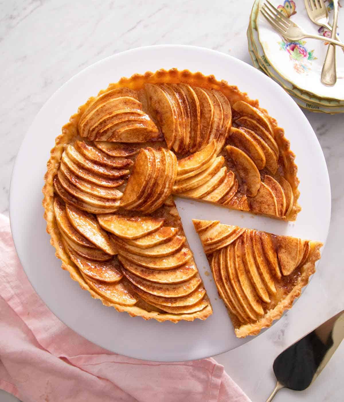 Overhead view of an apple tart with one slice cut out and move slightly away from it.