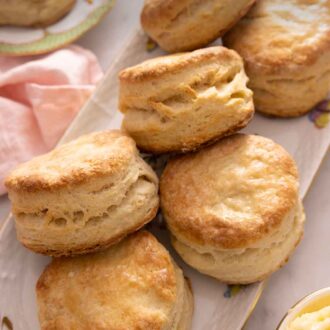 Pinterest graphic of a platter of six biscuits on top of a pink linen napkin.