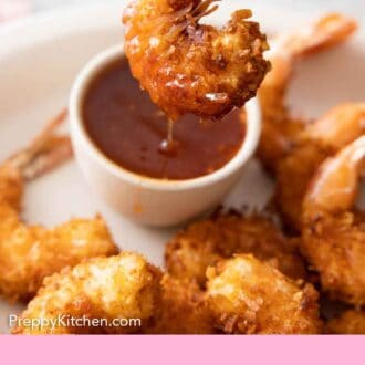 Pinterest graphic of a coconut shrimp dipped and lifted from sweet chili sauce.