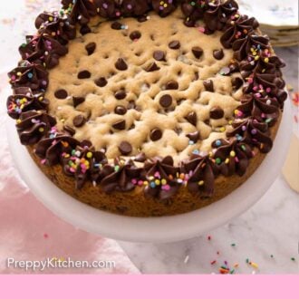 Pinterest graphic of a whole cookie cake on a cake stand with chocolate frosting and sprinkles.
