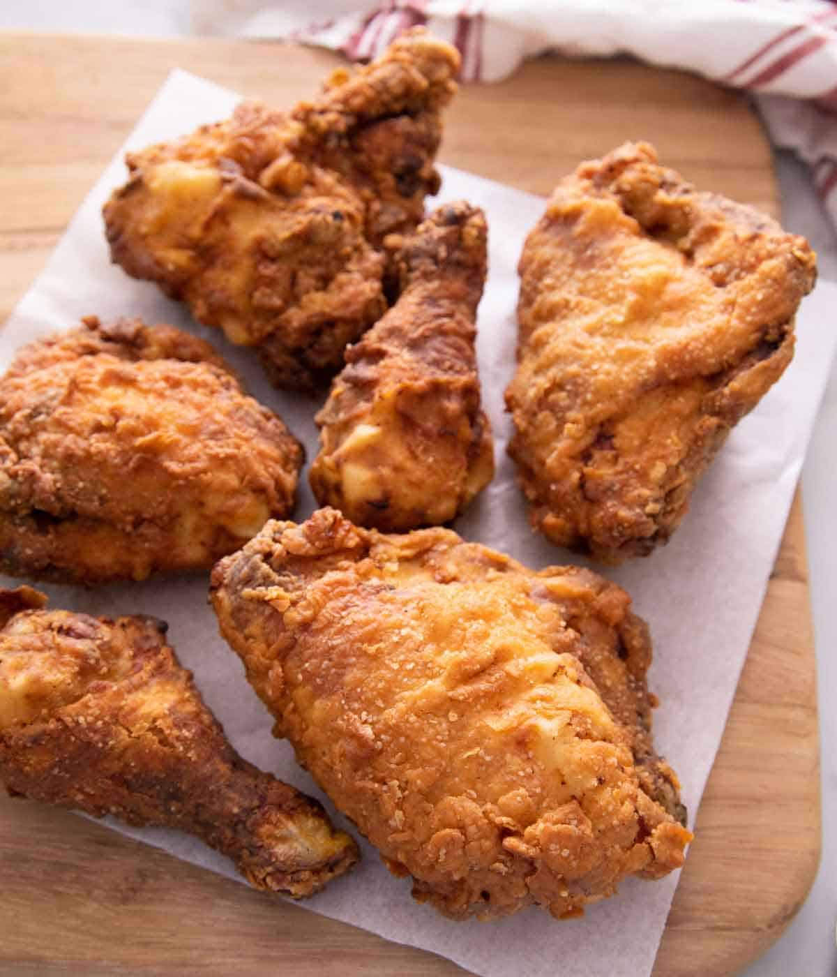 Six pieces of fried chicken on a paper towel on a cutting board.