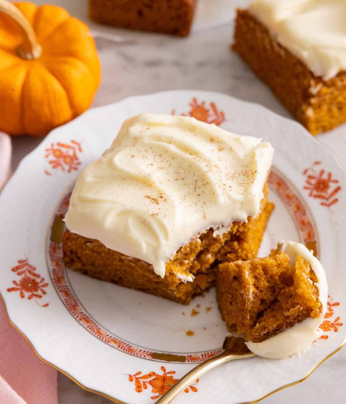 A square slice of pumpkin cake with a piece on a fork.