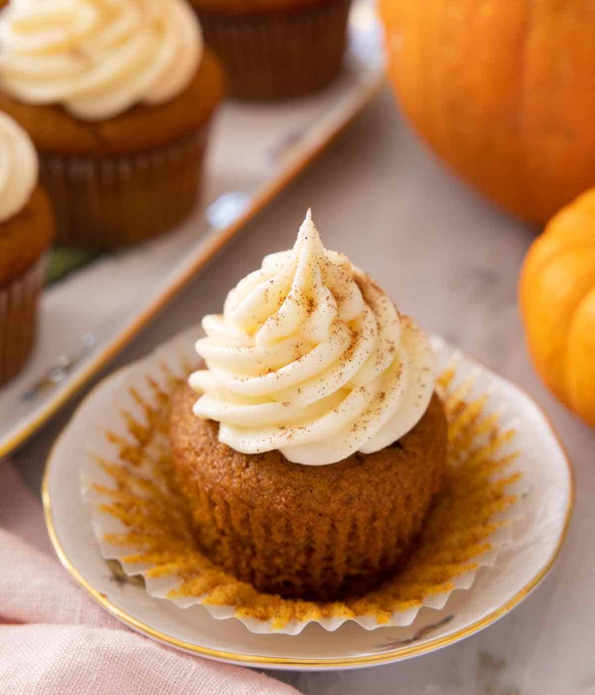 Close up of a pumpkin cupcake with cream cheese frosting on top.