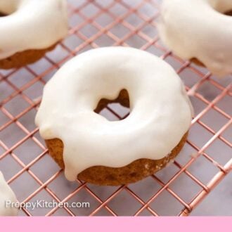 Pinterest graphic of glazed pumpkin donuts on a cooling rack.