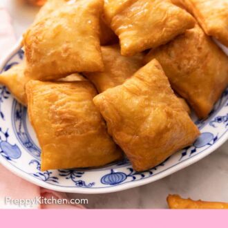 Pinterest graphic of a platter of sopapillas with a bowl of honey with a honey dipper in the background.