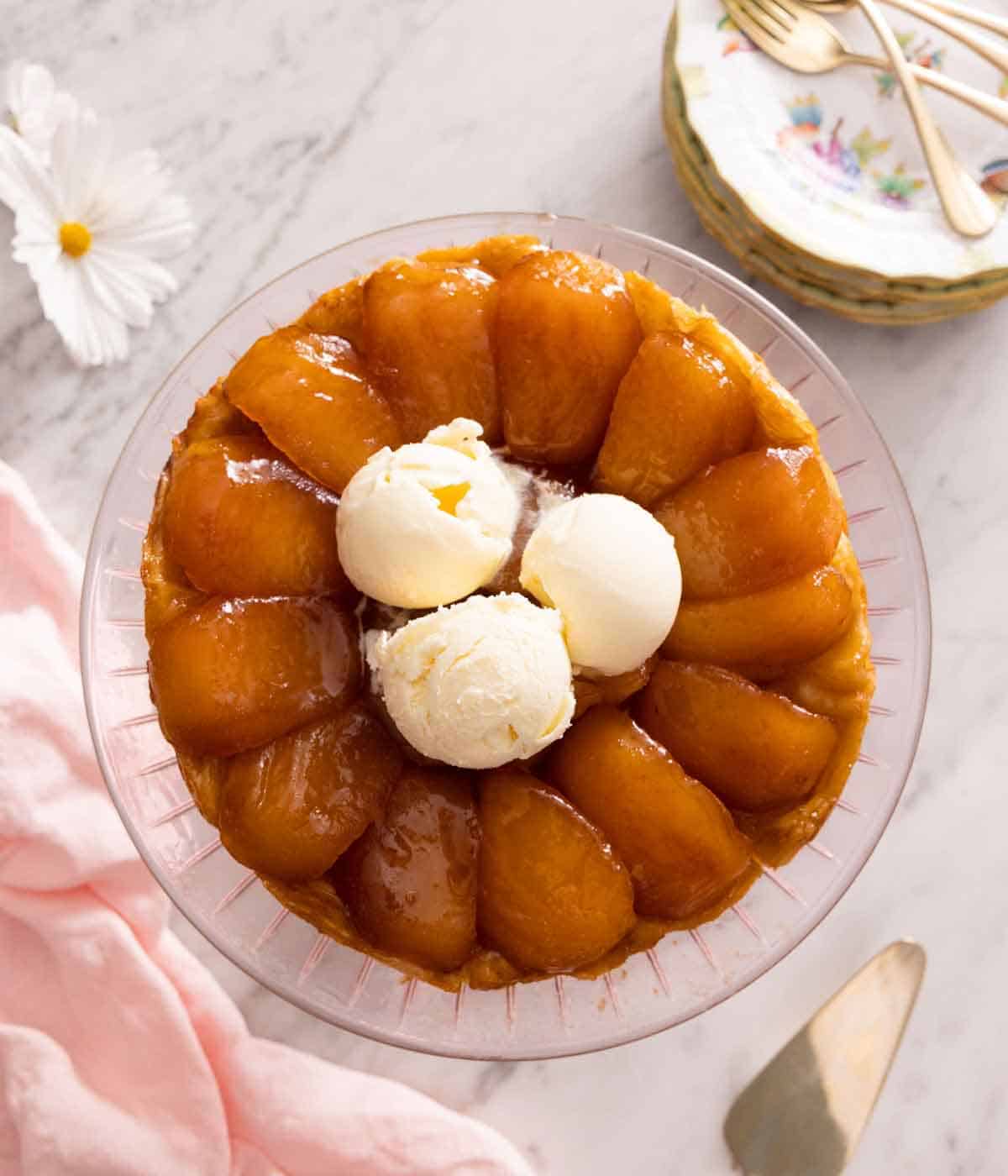 Overhead view of a tarte Tatin with three scoops of vanilla ice cream on top.