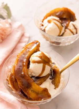 Two bowls of Banana Fosters, one in front has a spoon in it.