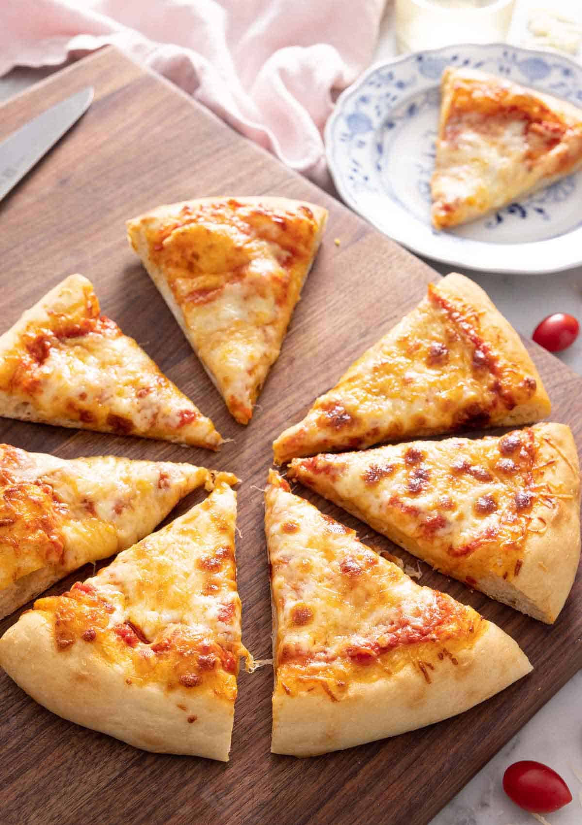 A cheese pizza sliced into 8 slices with 1 slice on a plate.