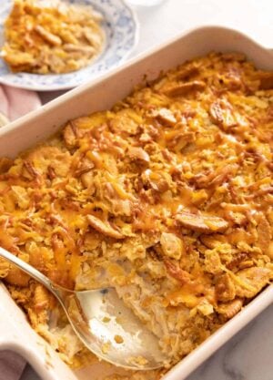 A chicken casserole with a serving removed and a spoon inside the baking dish.