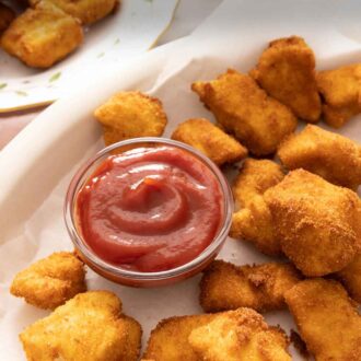 Pinterest graphic of a plate of chicken nuggets with a bowl of ketchup.