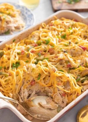 A casserole dish with chicken spaghetti and a spoon inside.