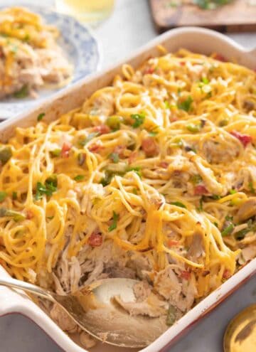 A casserole dish with chicken spaghetti and a spoon inside.