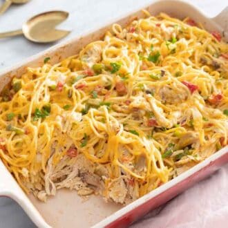 A baked chicken spaghetti casserole with a serving taken out.