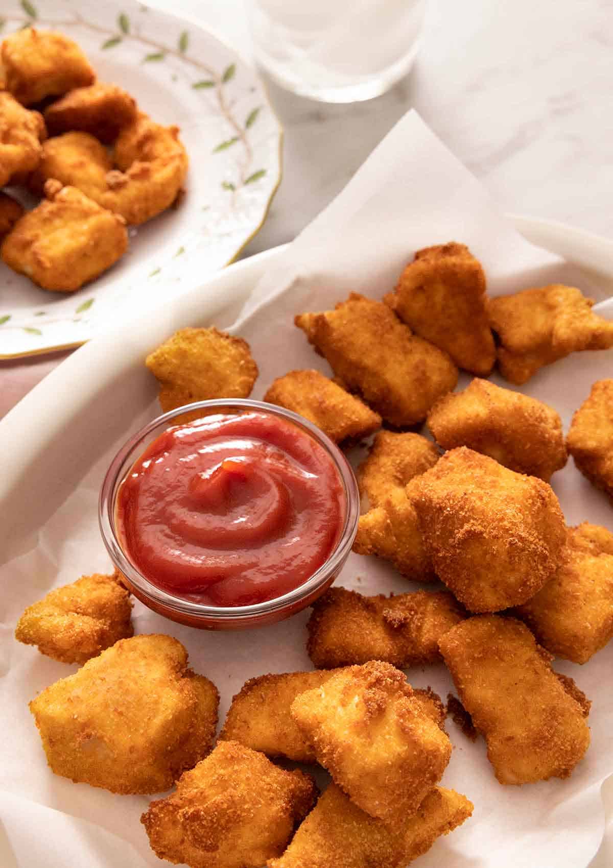 A plate of chicken nuggets with a bowl of ketchup.